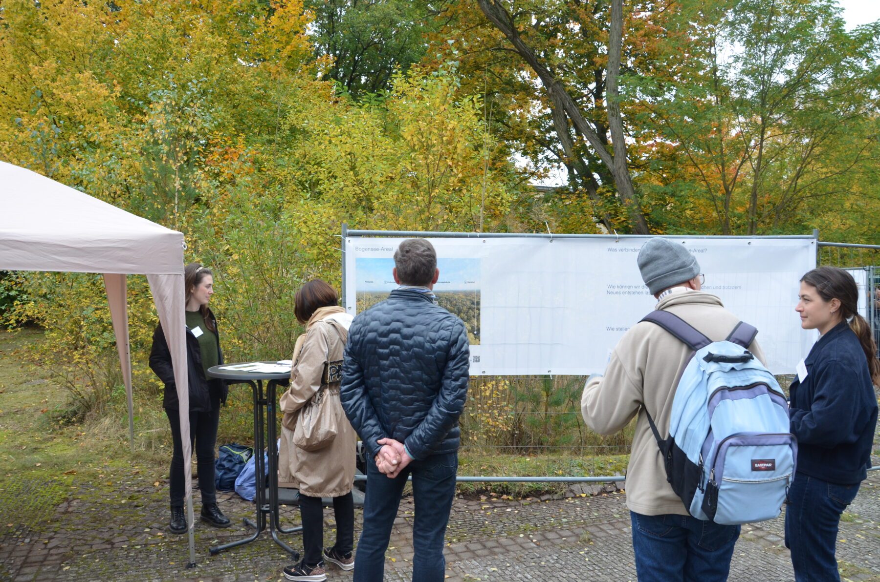 Fünf Menschen stehen vor einem Plakat.