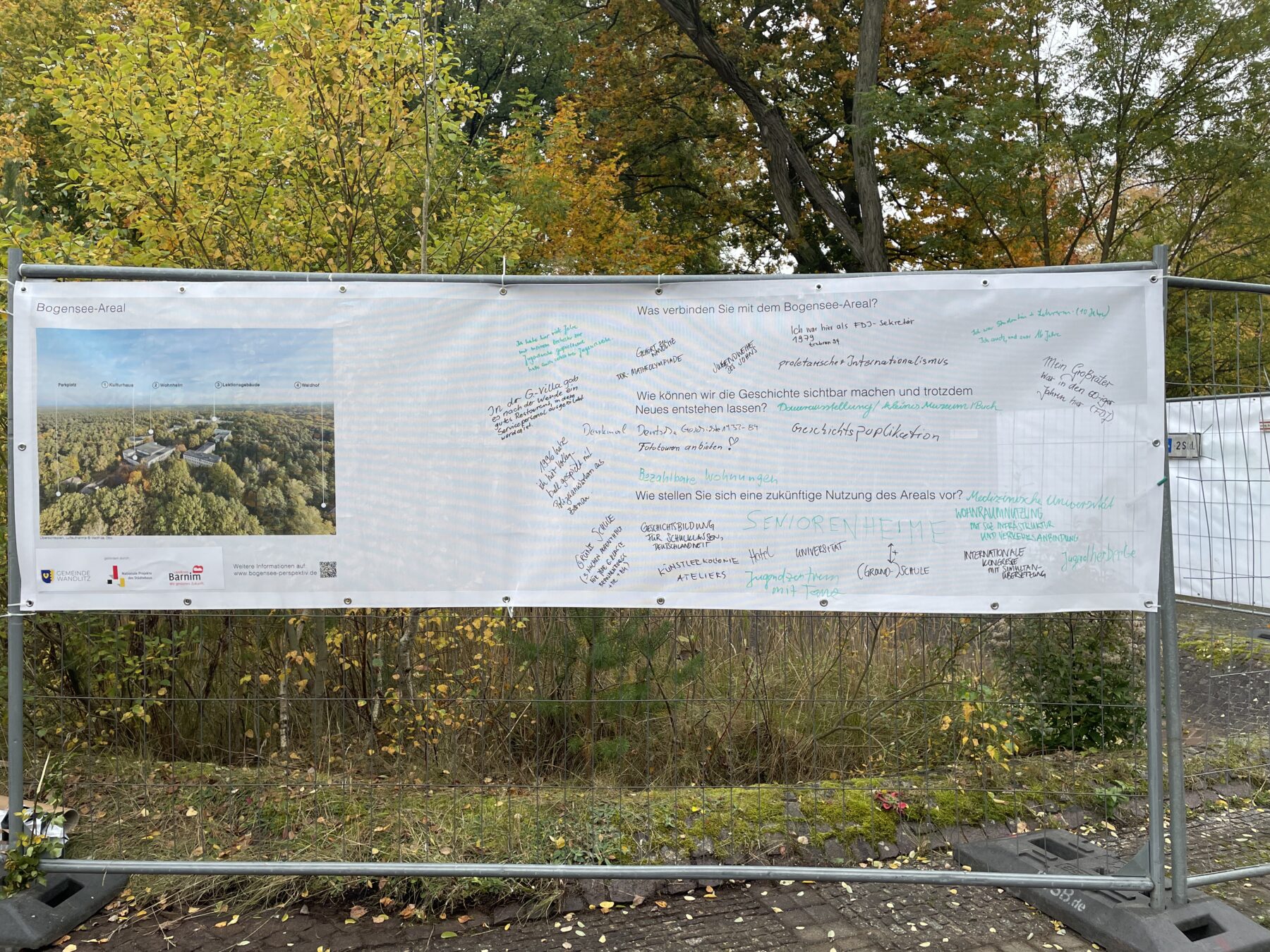 Ein handbeschriebenes Plakat hängt an einem Bauzaun.