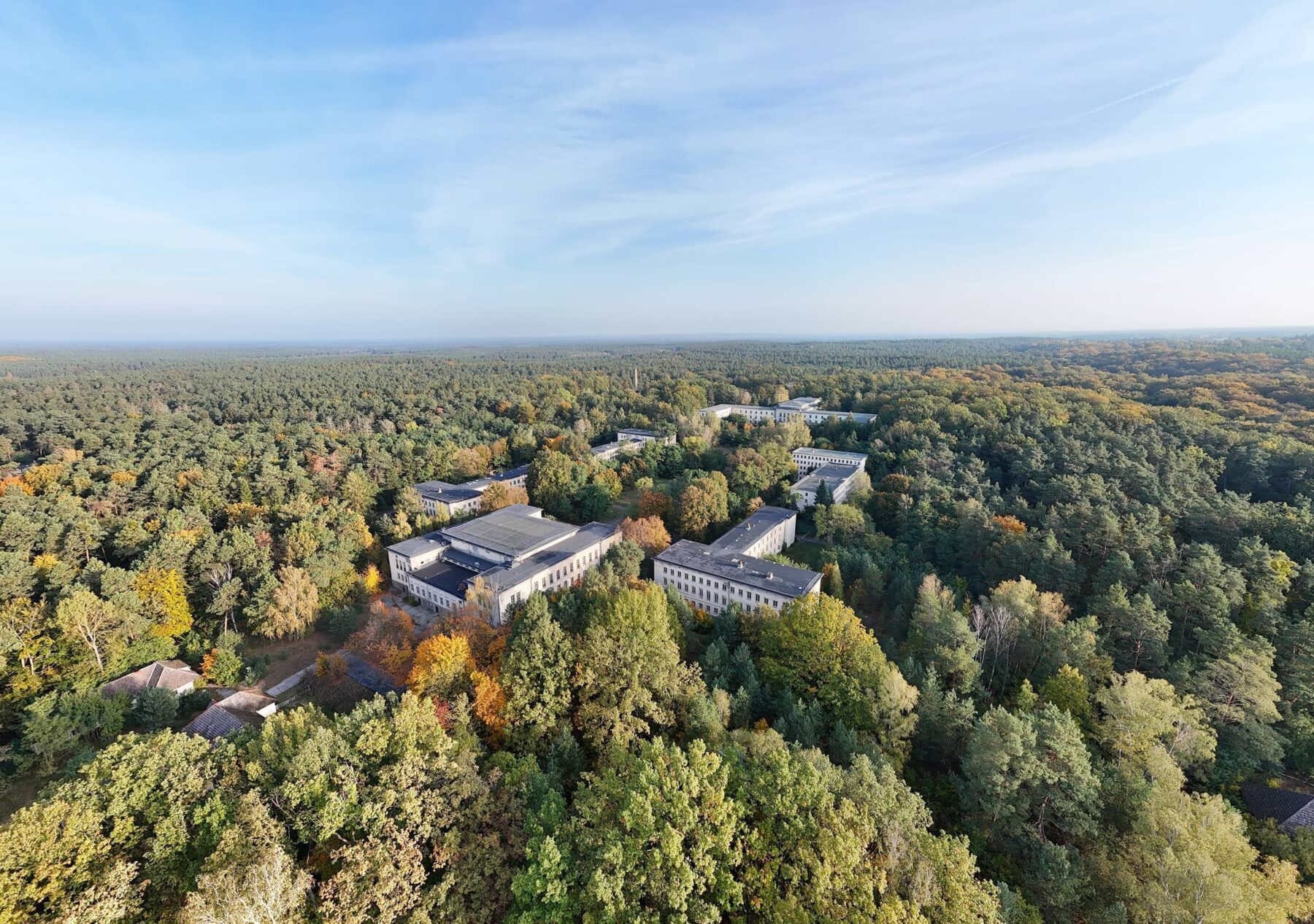 Ein Luftbild zeigt einen Wald und vereinzelte Gebäude.