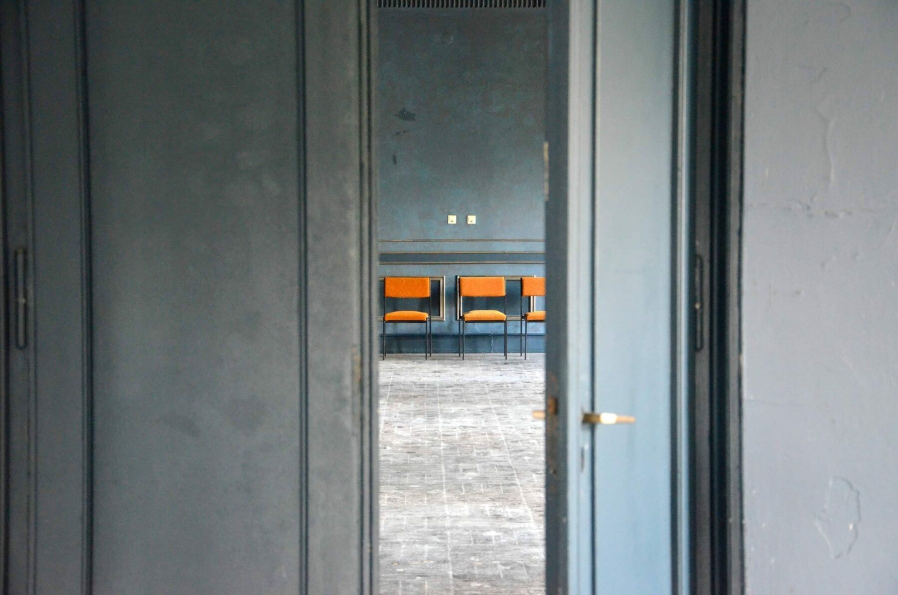 Eine Tür steht offen, im Hintergrund sind Stühle.